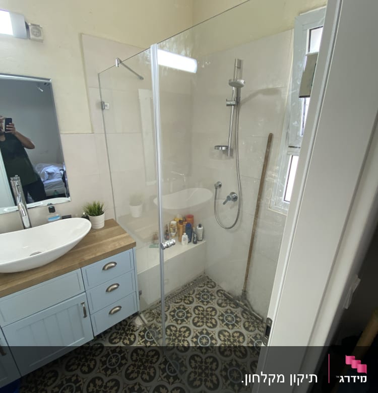 מקלחון זכוכית עם מוצרי טיפוח על המדף